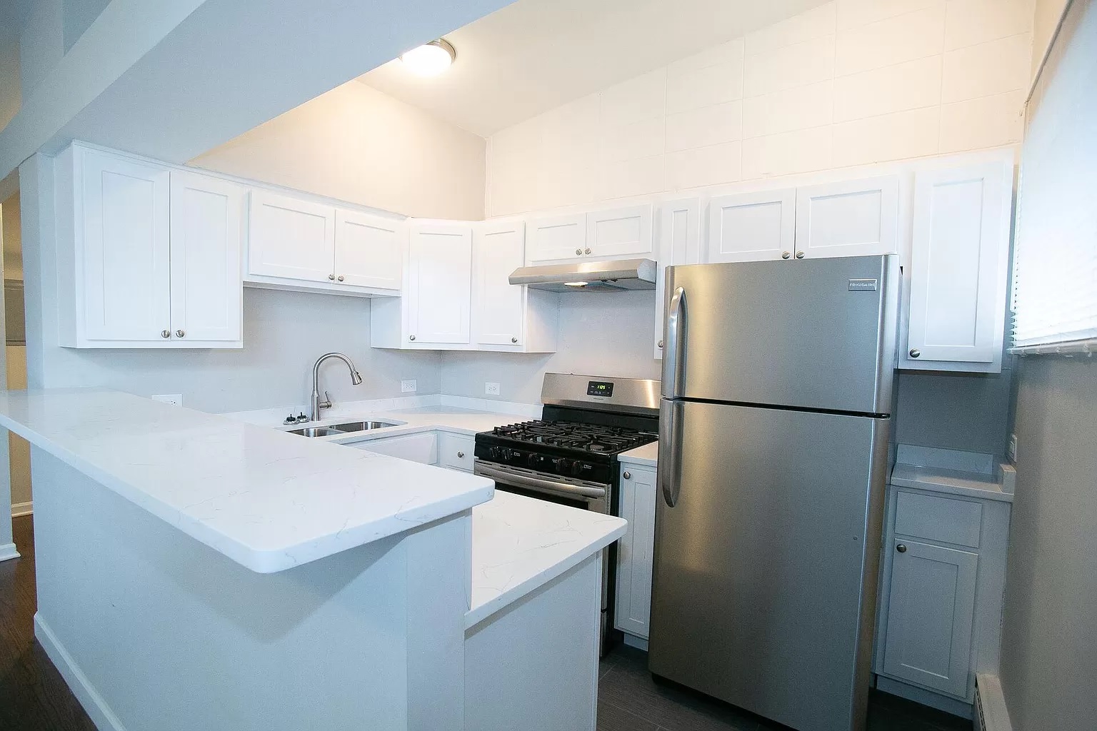 Arrival room of building, stacked brown cardboard boxes next to a black automated parcel locker and a windowed door, featu...